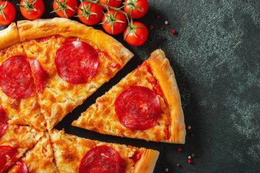 Lezzetli biberli pizza ve siyah beton arka planda domates fesleğeni. Acı biberli pizzanın en iyi manzarası. Metin için kopyalama alanı ile. Düz yatıyordu.