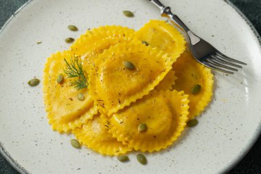 Hafif beton arka planda tereyağlı ev yapımı Balkabağı Ravioli. Üst görünüm.