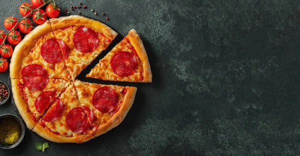 Νόστιμη πίτσα πεπερόνι και μαγειρικά συστατικά ντομάτες βασιλικός σε μαύρο σκυρόδεμα φόντο. Κάτοψη της καυτερής πίτσας πεπερόνι. Με χώρο αντιγραφής για κείμενο. Επίπεδη. Μπάνερ — Φωτογραφία Αρχείου