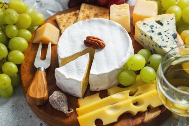 Tahta tabakta peynir tadı. Şarap ve romantik randevu için yemek, açık beton arka planda peynir şarküteri. Üst görünüm.