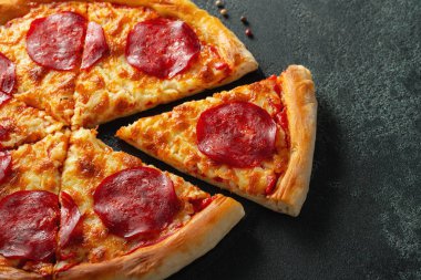 Lezzetli biberli pizza ve siyah beton arka planda domates fesleğeni. Acı biberli pizzanın en iyi manzarası. Metin için kopyalama alanı ile.