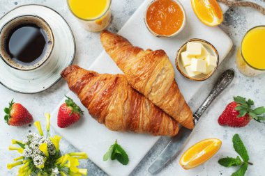 Kahvaltıda tereyağlı ve portakal reçelli taze kruvasan. Beyaz beton bir masada Avrupalı kahvaltısı. Üst Manzara. Düz yatıyordu