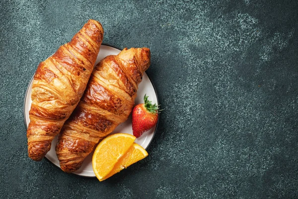 Friss édes croissant vajjal és narancslekvárral reggelire. Kontinentális reggeli egy fekete betonasztalon. Felülnézet fénymásoló felülettel. Lapos fektetés — Stock Fotó