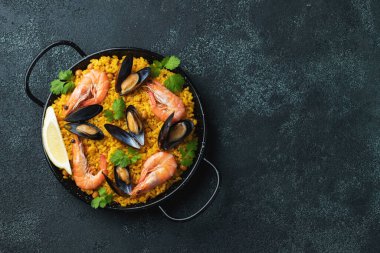 Geleneksel İspanyol deniz ürünleri paella tavada nohut, karides, midye, siyah beton arka planda mürekkep balığı. Kopyalama alanı olan üst görünüm.
