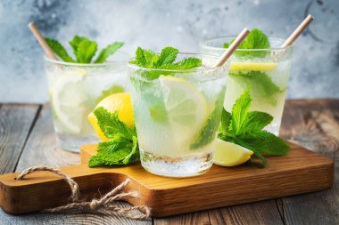 İki bardak limonata ya da naneli mojito kokteyli soğuk, ferahlatıcı içecek ya da buzlu, mavi arka planda buzlu içecek.