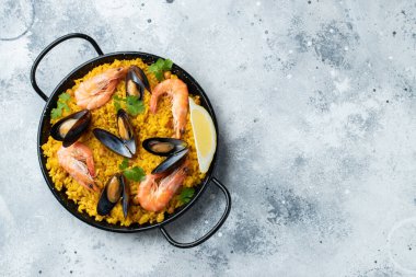Geleneksel İspanyol deniz ürünleri paella tavada nohut, karides, midye, açık gri beton arka planda mürekkep balığı. Kopyalama alanı olan üst görünüm