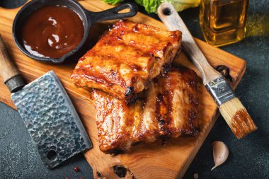 Baharatlı, ızgara pirzola. Barbekü, acı biber ve taze domatesle servis edilir. Eski bir ahşap kesim tahtasının üzerinde.