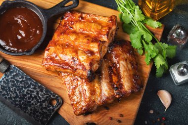 Baharatlı, ızgara pirzola. Barbekü, acı biber ve taze domatesle servis edilir. Eski bir ahşap kesim tahtasının üzerinde.