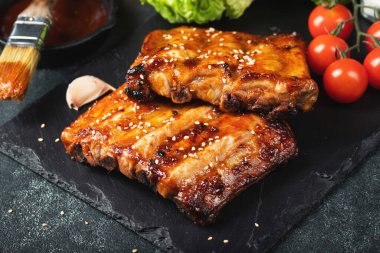 Barbekü domuz pirzolası ve siyah arka planda sıcak bal biberli terbiye..