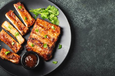 Barbekü soslu bir tabakta servis edilen sıcak ızgara pirzola. Üst Manzara. Boşluğu kopyala.