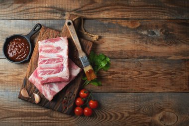 Baharatlı çiğ domuz pirzolası, siyah ahşap arka planda tuz ve biberiye. Kopyalama alanı olan üst görünüm.