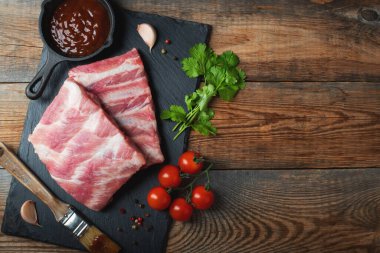 Baharatlı çiğ domuz pirzolası, siyah ahşap arka planda tuz ve biberiye. Kopyalama alanı olan üst görünüm.