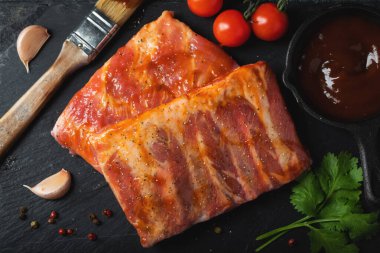 Barbekü, çiğ domuz pirzolası ve barbekü sosu hazır. Siyah arka plan. Üst görünüm.