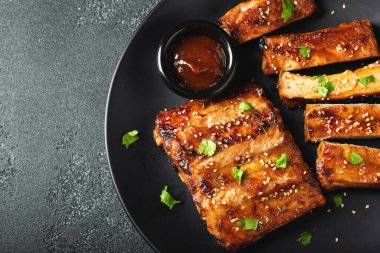 Barbekü soslu bir tabakta servis edilen sıcak ızgara pirzola. Üst Manzara. Boşluğu kopyala.