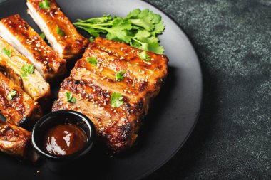 Barbekü soslu bir tabakta servis edilen sıcak ızgara pirzola. Üst Manzara. Boşluğu kopyala.