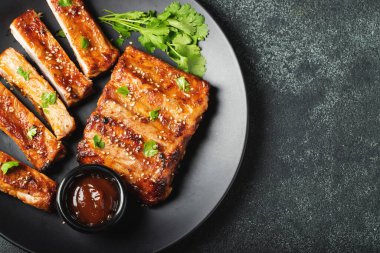 Barbekü soslu bir tabakta servis edilen sıcak ızgara pirzola. Üst Manzara. Boşluğu kopyala.