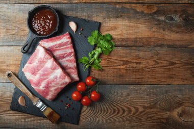 Baharatlı çiğ domuz pirzolası, siyah ahşap arka planda tuz ve biberiye. Kopyalama alanı olan üst görünüm.