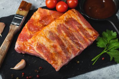 Barbekü, çiğ domuz pirzolası ve barbekü sosu hazır. Siyah arka plan. Üst görünüm.