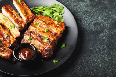 Barbekü soslu bir tabakta servis edilen sıcak ızgara pirzola. Üst Manzara. Boşluğu kopyala.