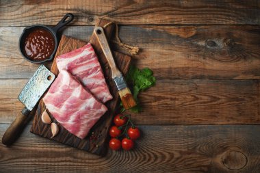 Baharatlı çiğ domuz pirzolası, siyah ahşap arka planda tuz ve biberiye. Kopyalama alanı olan üst görünüm.