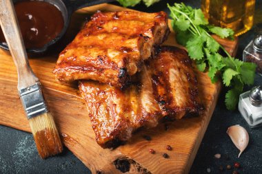 Baharatlı, ızgara pirzola. Barbekü, acı biber ve taze domatesle servis edilir. Eski bir ahşap kesim tahtasının üzerinde.