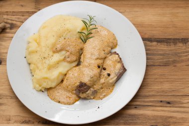 Kızarmış domuz sos ve beyaz plaka üzerinde patates püresi ile
