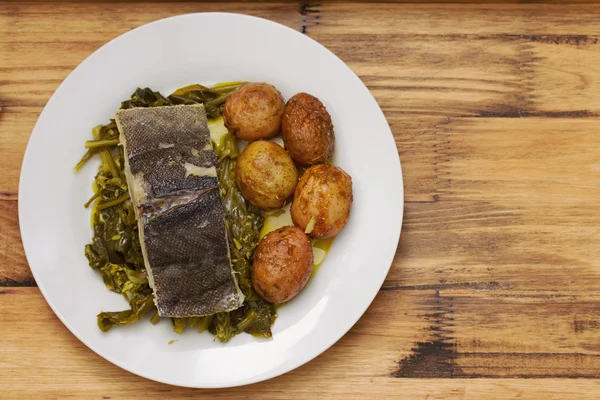 Рыба с картошкой и овощами на белой тарелке — стоковое фото
