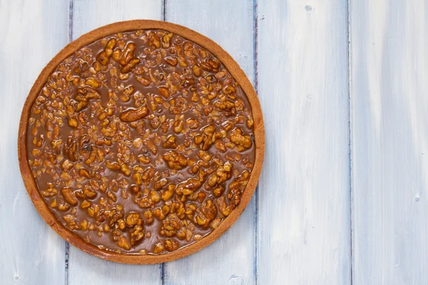Nakrętki tarta z karmelu na brązowym tle drewniane — Zdjęcie stockowe