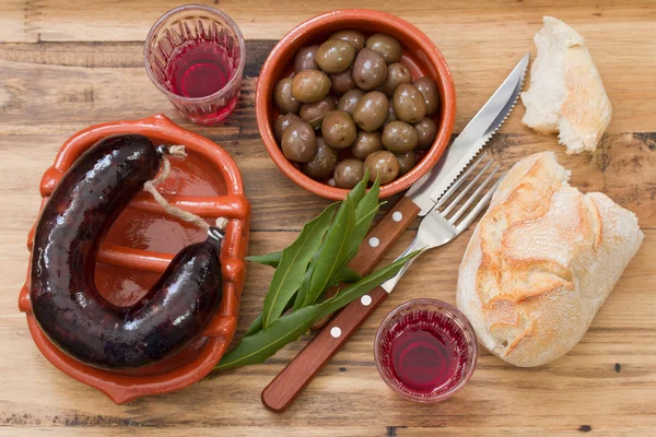 Smoked sausage on ceramic dish with olives, bread and wine — Stock Photo, Image