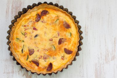 Beyaz ahşap zemin üzerinde füme sosis ile tart