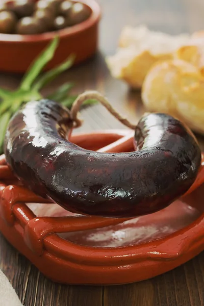 Saucisse fumée sur un plat en céramique aux olives — Photo