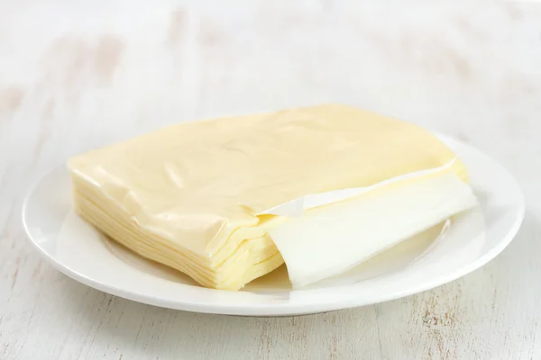 Beyaz ahşap zemin üzerinde plaka üzerinde peynir — Stok fotoğraf