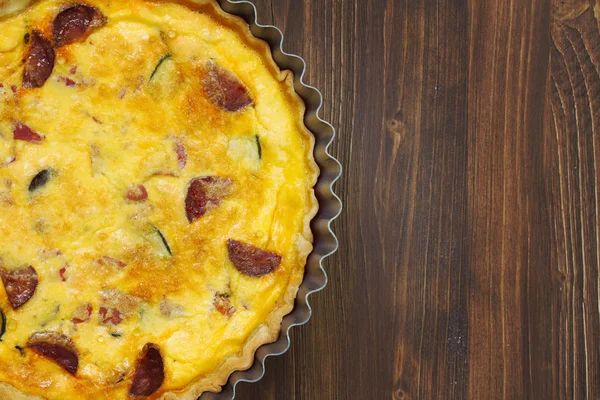 Tart with smoked sausages on brown wooden background — Stock Photo, Image