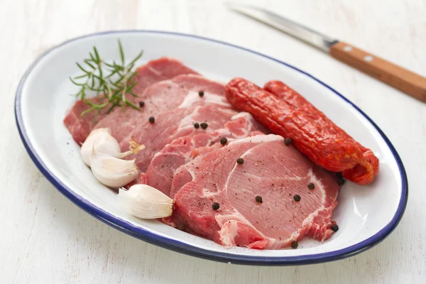 Pork with black pepper, smoked sausages and garlic on dish and knife — Stock Photo, Image