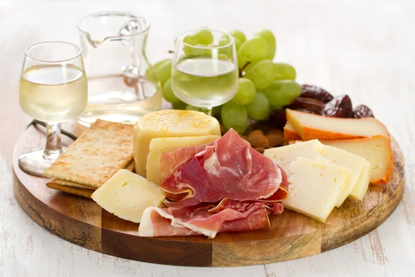 Presunto com queijo e vinho branco em tábua de madeira — Fotografia de Stock