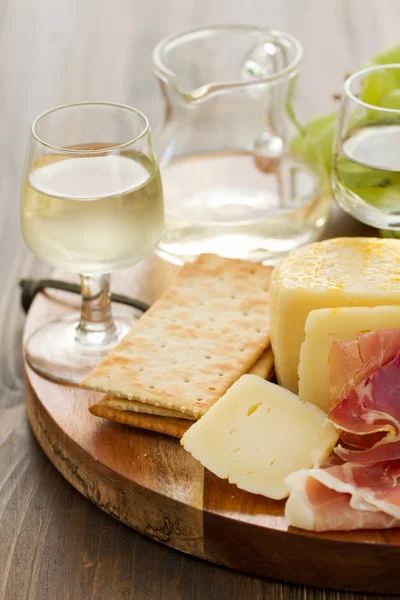 Queijo e vinho branco em tábua de madeira — Fotografia de Stock