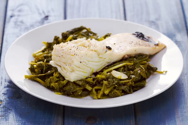 Cod fish with turnip greens on white plate — Stock Photo, Image