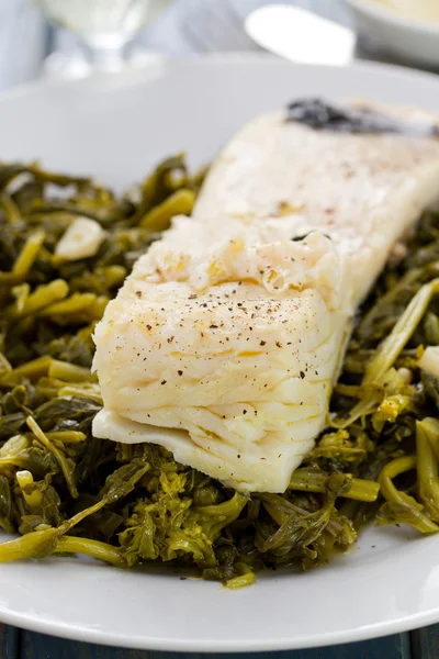 Codfish with olives and greens on white plate — Stock Photo, Image