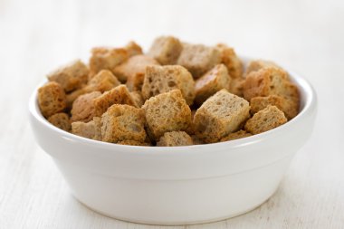 Beyaz ahşap zemin üzerinde beyaz tabak içinde croutins