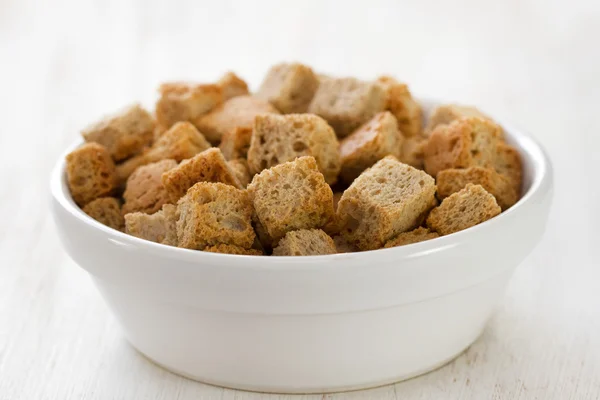 Crostini in piatto bianco su fondo bianco in legno — Foto Stock