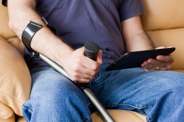 Homem com muletas segurando tablet — Fotografia de Stock