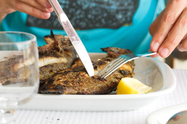 Homem comendo peixe grelhado no prato branco — Fotografia de Stock