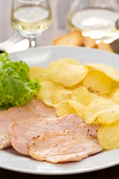 Gebratenes Fleisch mit Kartoffelchips und frischem Salat auf weißem Teller auf braunem Hintergrund — Stockfoto