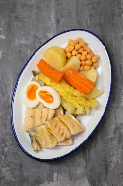 Haşlanmış sebzeli haşlanmış balık ve beyaz tabakta yumurta.