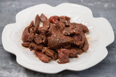 Beyaz tabakta soslu kızarmış et.