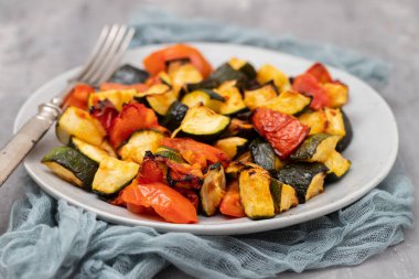 Fırında kabak ve domates tabakta çatal ve seramik zemin üzerinde bıçak.