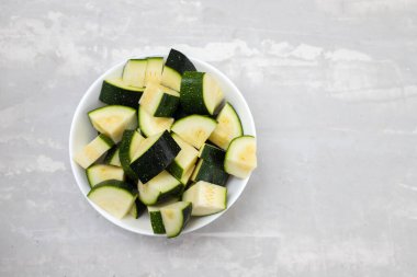 Seramik arka planda küçük beyaz kâse içinde taze kabak.