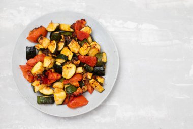 Fırında kabak ve domates tabakta çatal ve seramik zemin üzerinde bıçak.