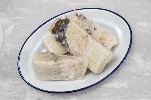 Замороженной трески рыбы на белом блюде на керамическом фоне — стоковое фото