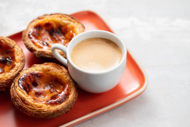 Tipik Portekiz yumurtalı tart pastel de nata ve bir fincan kahve.